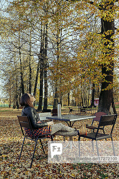 Frau  die an einem sonnigen Tag im Park sitzt und nach oben schaut