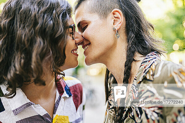 Young lesbian couple nuzzling nose to nose on sunny day