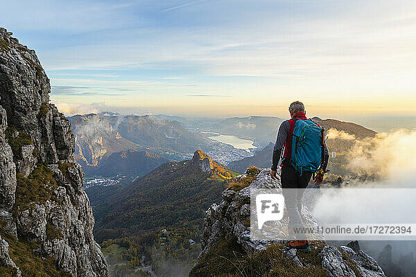Pensive male hiker walking on mountain peak during sunrise at Bergamasque Alps  Italy