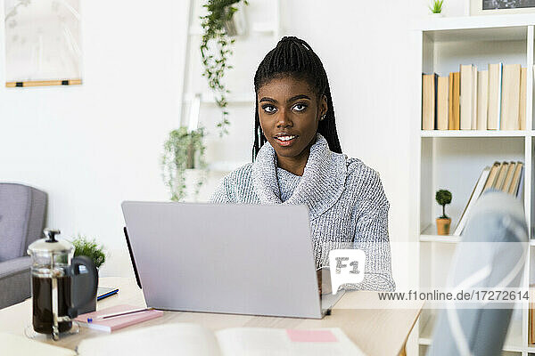 Young woman studying through laptop while sitting at home