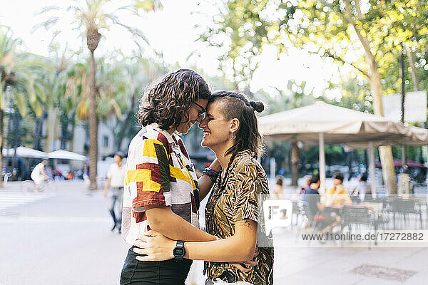 Glückliches lesbisches Paar kuschelt auf dem Fußweg bei Sonnenschein an der Nase