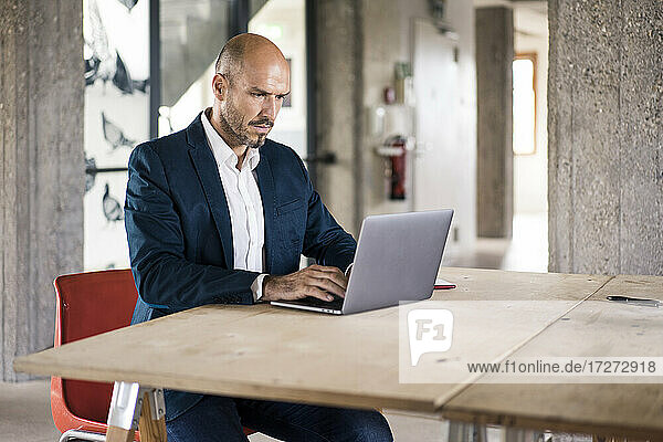 Businessman wearing suit using laptop while working at office