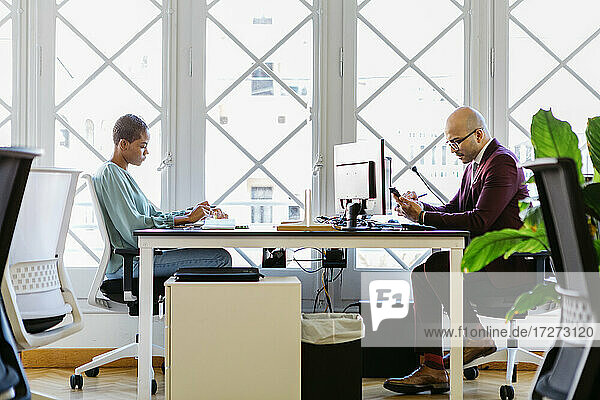Business professionals working at desk against window in office