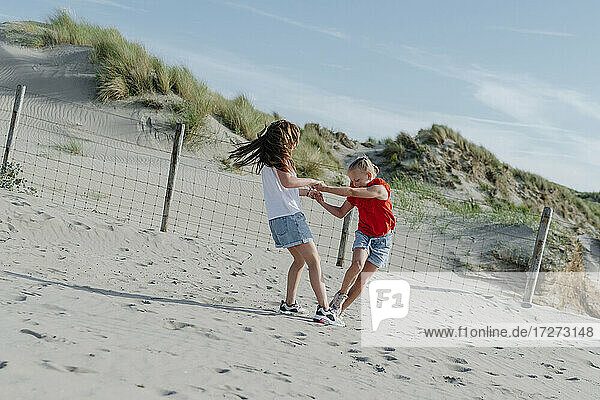Sisters playing on sand at beach during sunny day