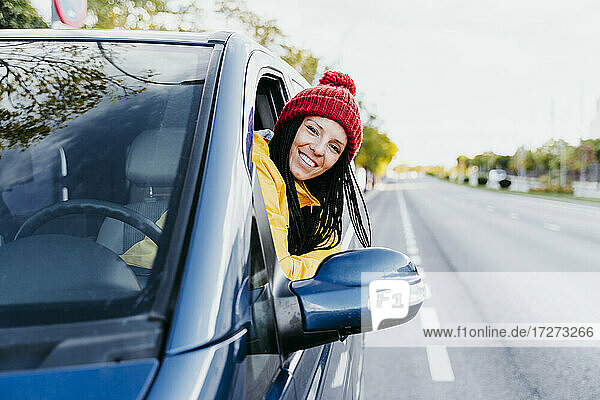 Smiling woman leaning on car window during road trip