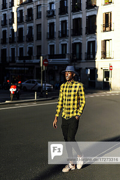 Confident african man with hands in pockets walking in city