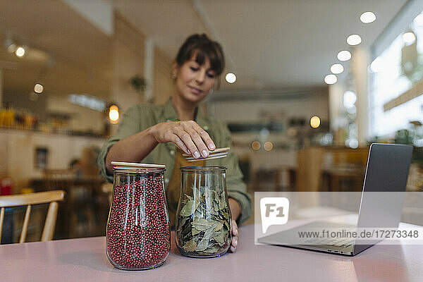Weibliche Besitzerin beim Schließen eines auf dem Tisch im Café aufbewahrten Blattglases