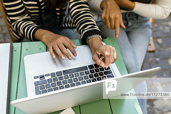 Geschäftsfrauen  die einen Laptop benutzen und in einem Café diskutieren