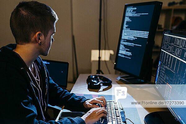 Male hacker looking at computer while working at office