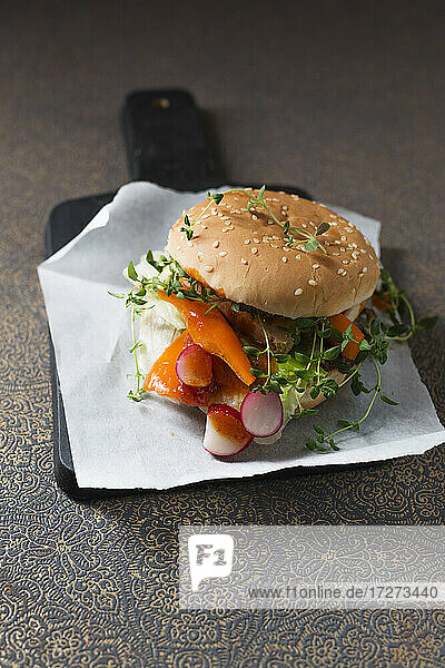 Veganer Burger mit Sojaschnitzelstreifen  Paprika  Radieschen  Oregano und Kopfsalat