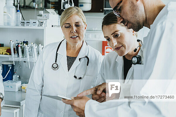 Ein männlicher und ein weiblicher Wissenschaftler benutzen ein digitales Tablet  während sie im Labor stehen