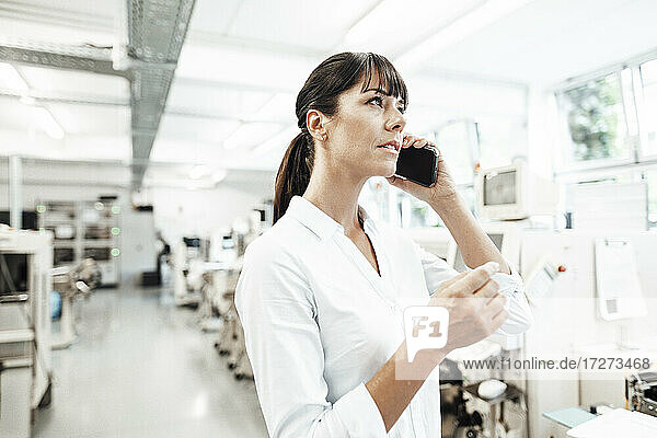 Businesswoman talking on smart phone while looking away in industry