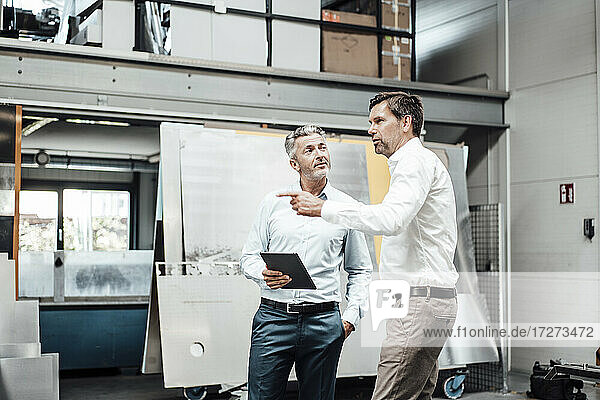 Mature businessman pointing while explaining colleague in industry