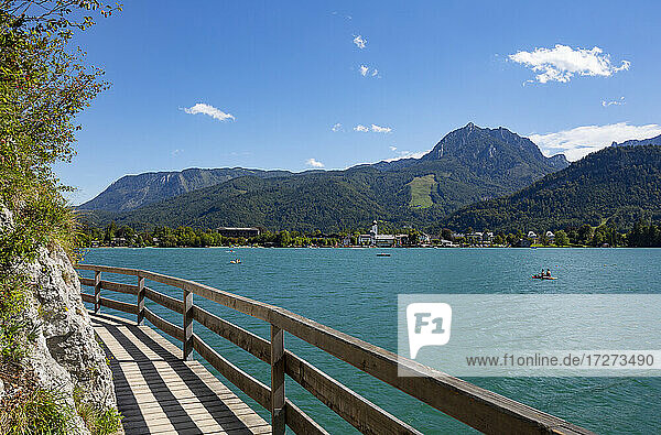 Austria  Salzburg  Strobl Am Wolfgangsee  Boardwalk stretching along shore of Lake Wolfgangsee in summer with forested mountains in background