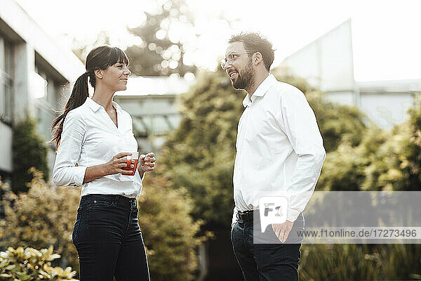 Smiling male and female colleagues talking while taking break at industry