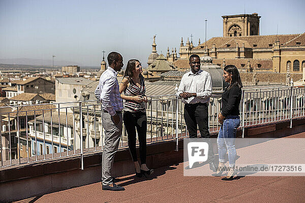 Lächelnde männliche und weibliche Unternehmer diskutieren in der Pause auf dem Dach eines Bürogebäudes