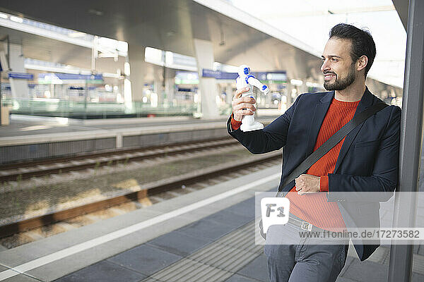 Smiling entrepreneur looking at robot while standing on railroad platform