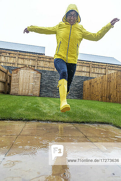 Fröhliche Frau  die während der Regenzeit im Hinterhof springt