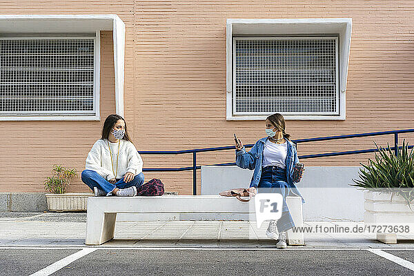 Freund fotografiert Teenager-Mädchen  das auf einer Betonbank sitzt