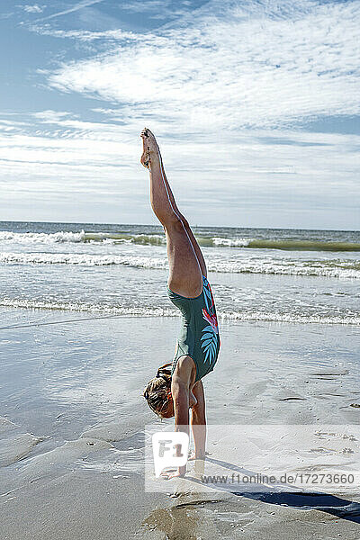Mädchen Turner tun upside auf Sand am Strand während sonnigen Tag