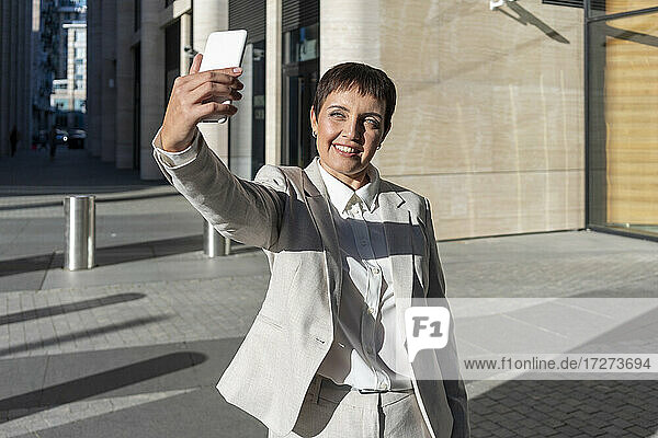 Frau nimmt Selfie  während gegen Bürogebäude stehen