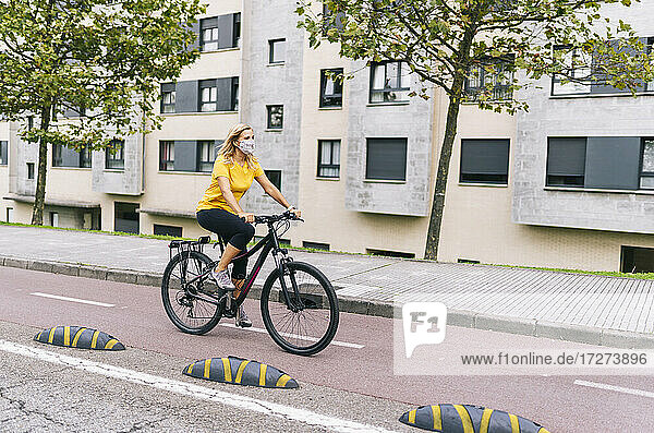 Ältere Frau fährt auf dem Fahrradweg in der Stadt während COVID-19