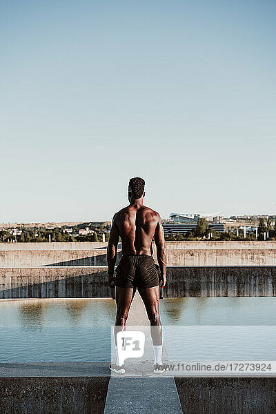 Sportsman standing on wall against clear blue sky during sunny day