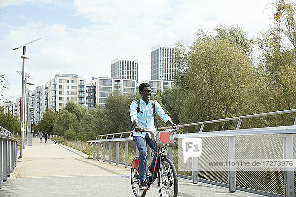 Lächelnder Mann beim Pendeln mit dem Fahrrad in der Stadt