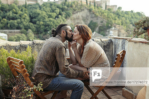 Paar küsst auf einem Stuhl sitzend auf dem Dach
