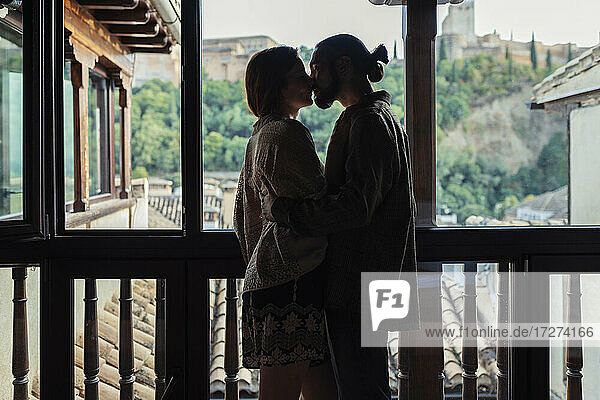 Paar  das sich küsst  während es am Fenster zu Hause steht