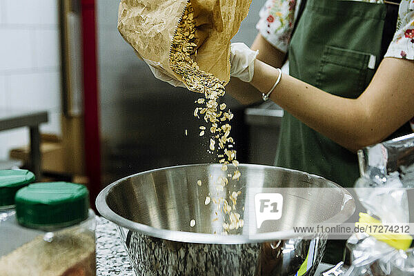 Bäckerin gießt Zutaten in eine Schüssel in einer Bäckereiküche