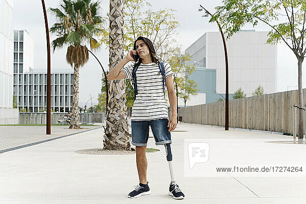Mann mit Beinprothese spricht in der Stadt mit einem Smartphone