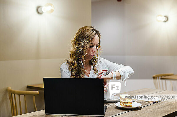 Geschäftsfrau benutzt Smartwatch  während sie am Tisch sitzt