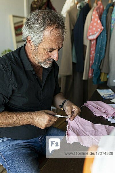 Mature tailor working at table in studio