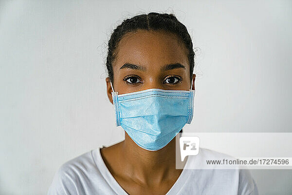 Teenager-Mädchen mit Gesichtsschutzmaske  das während des Covid-19 an der Wand steht