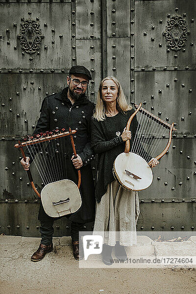 Männliches und weibliches Paar  das ein Lyra-Musikinstrument gegen eine Metalltür hält