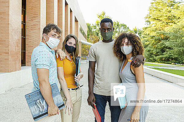 Universitätsstudenten tragen Schutzmasken  während sie auf dem Campus stehen