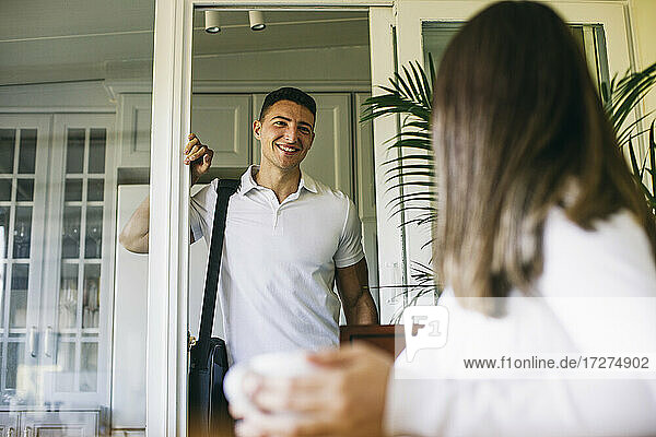 Smiling man looking at woman while standing at home
