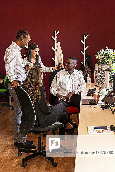 Lächelnde multiethnische männliche und weibliche Kollegen diskutieren bei einer Besprechung im Büro