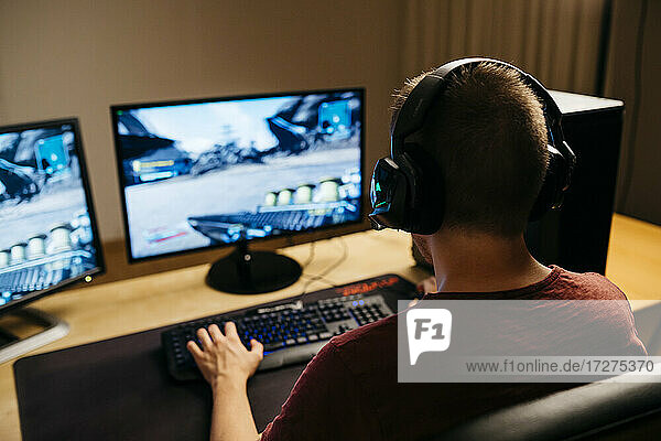Junger Mann spielt Videospiele mit Computer am Schreibtisch