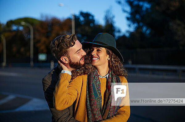 Lächelnder Mann  der eine Frau von hinten umarmt  während er in der Stadt steht