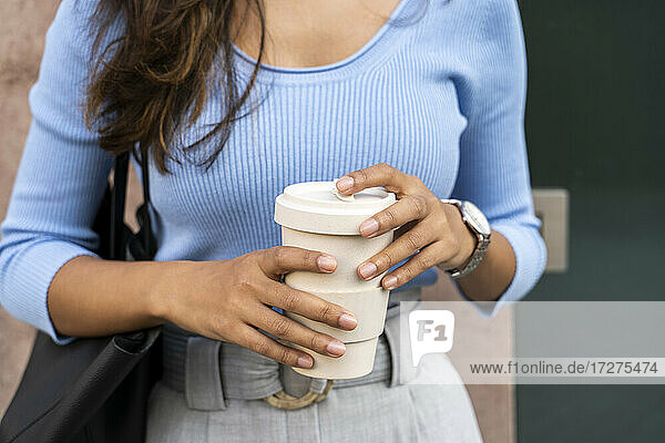 Junge Frau hält Einweg-Kaffeebecher
