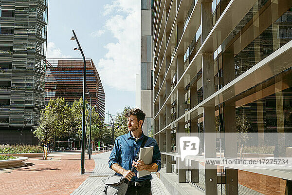 Geschäftsmann schaut weg  während er auf dem Fußweg neben einem modernen Bürogebäude geht