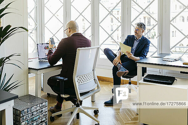 Businessmen working at desk against window in office