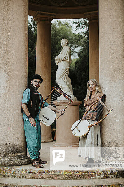 Männliches und weibliches Paar  das ein Lyra-Musikinstrument an einer Säule hält