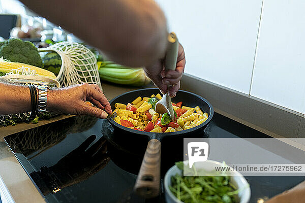 Menschliche Hand bei der Zubereitung von Nudeln in der Küche