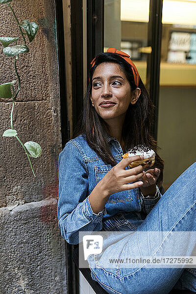 Junge Frau isst Wüste  während sie in einem Café am Fenster sitzt