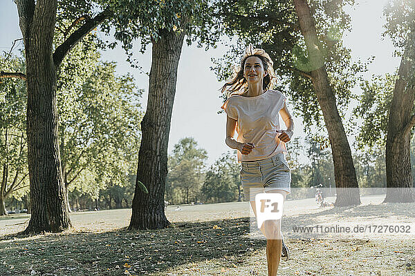 Ältere Frau joggt im öffentlichen Park an einem sonnigen Tag