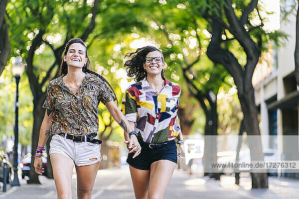 Lächelndes lesbisches Paar beim Laufen auf dem Fußweg in der Stadt