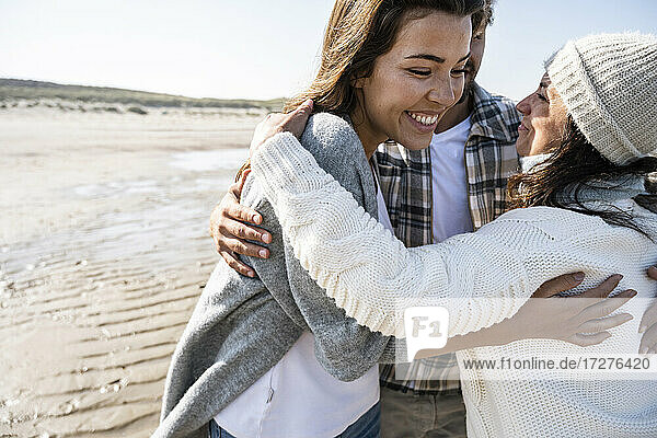 Reife Frau umarmt Paar  während sie am Strand steht